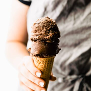A double scoop espresso dark chocolate sorbet in waffle cone being held