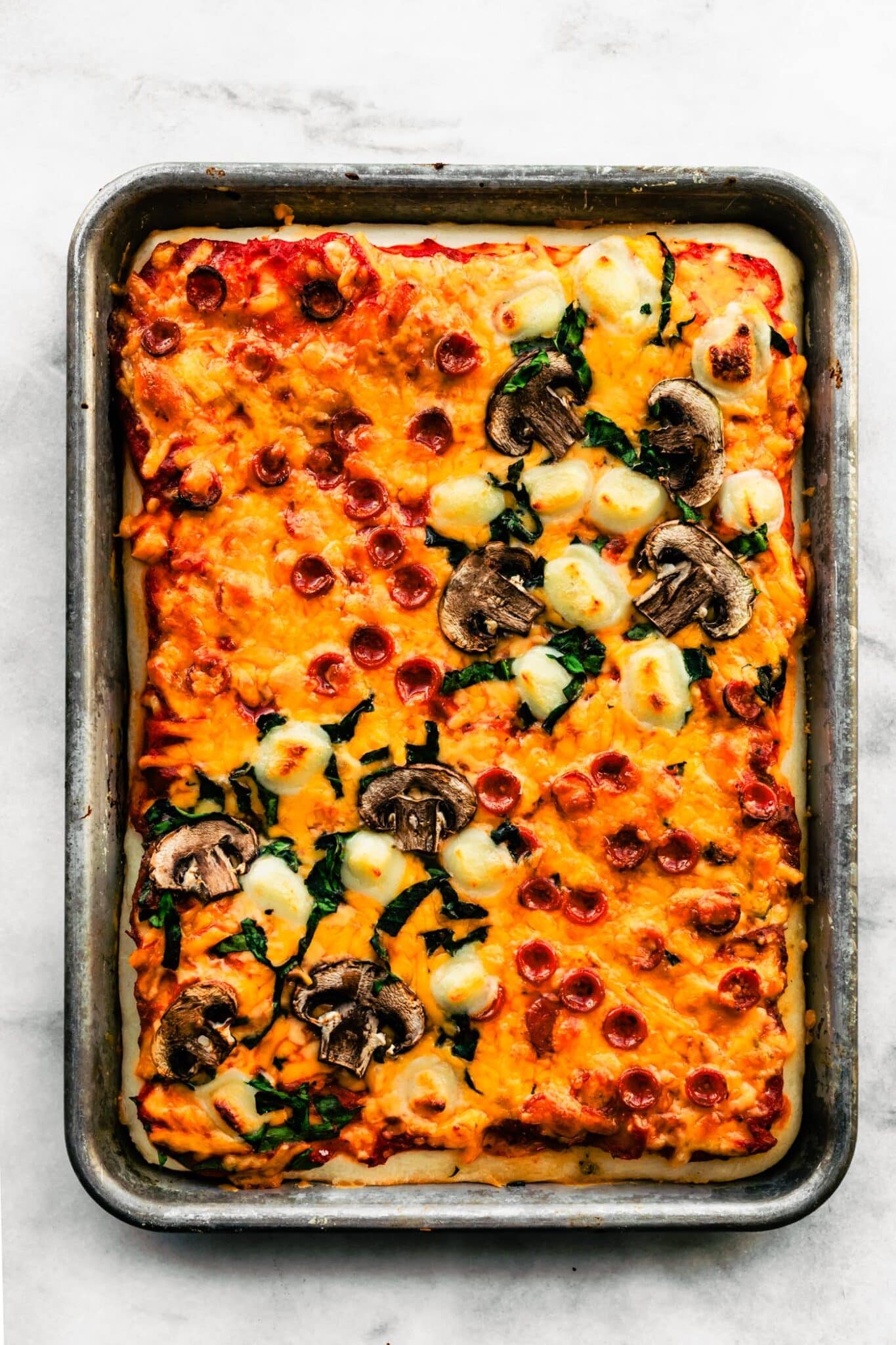 A sheet pan pizza topped with mushrooms, cheese and pepperoni.