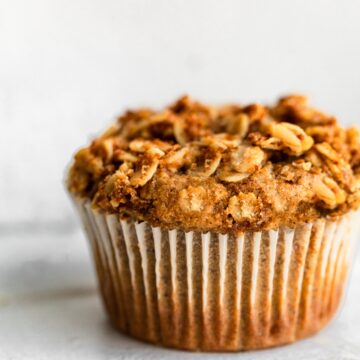Up close photo of a fluffy honey ricotta muffin in a paper liner.