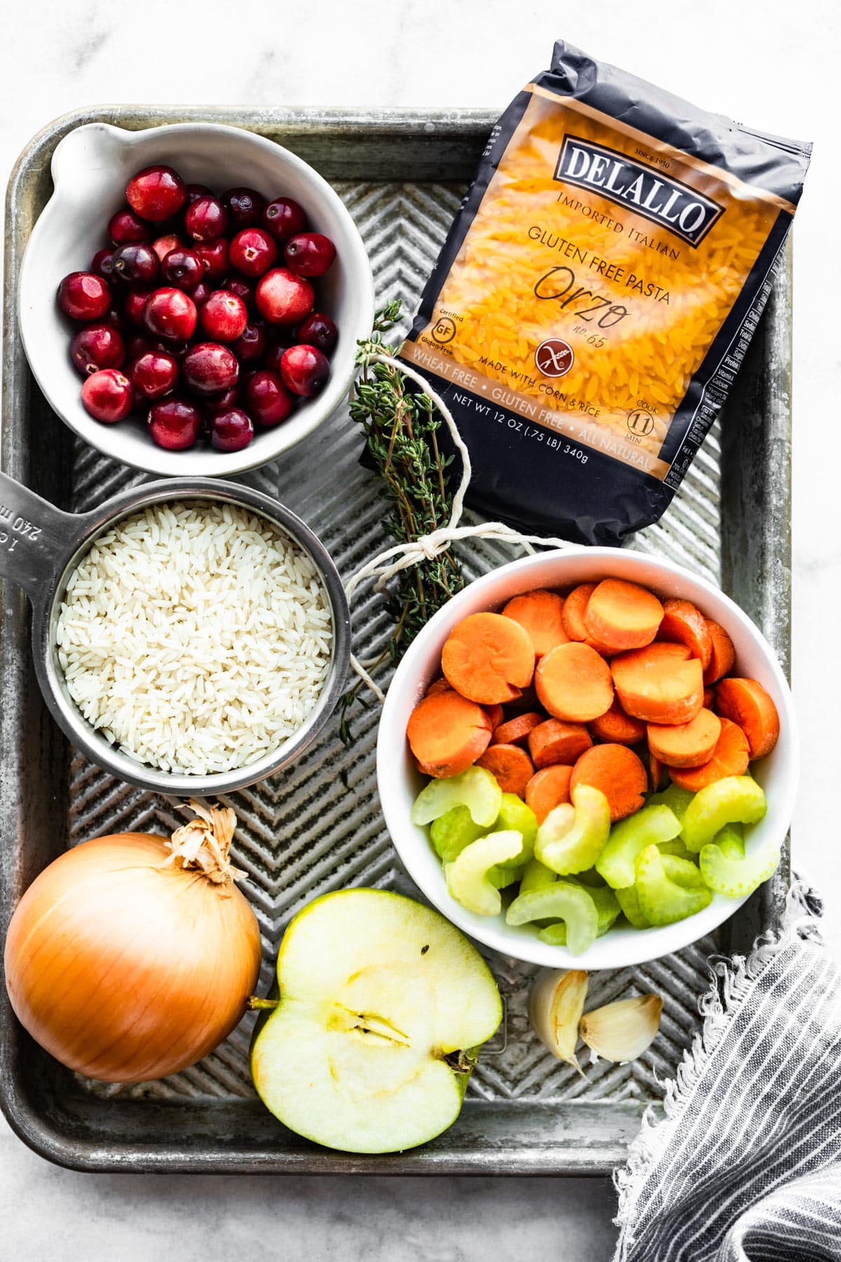 cranberries, delallo gluten free orzo, long grain rice, an onion, half an apple, and diced carrots and celery