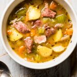 Overhead photo of Irish Lamb Stew in a white bowl with a spoon beside it.