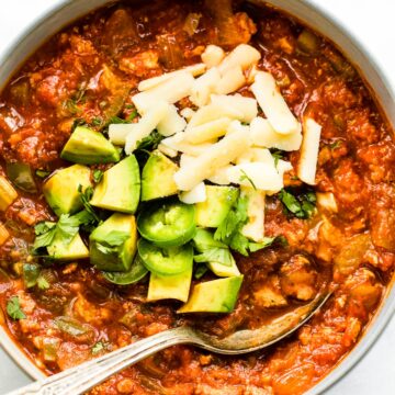 Overhead photo of a bowl of no bean chili topped with cheese, avocado and jalapenos.