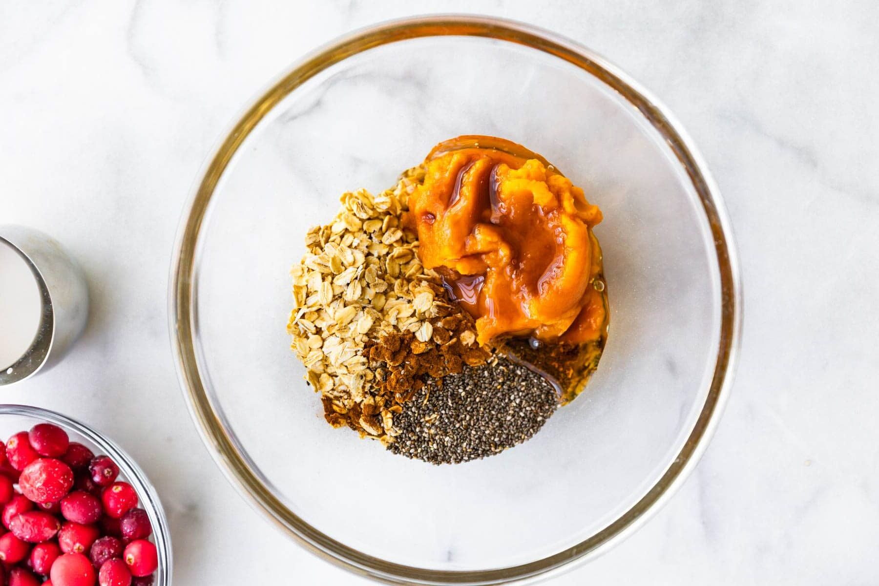 overhead photo of ingredients for overnight pumpkin oats in a glass mixing bowl.