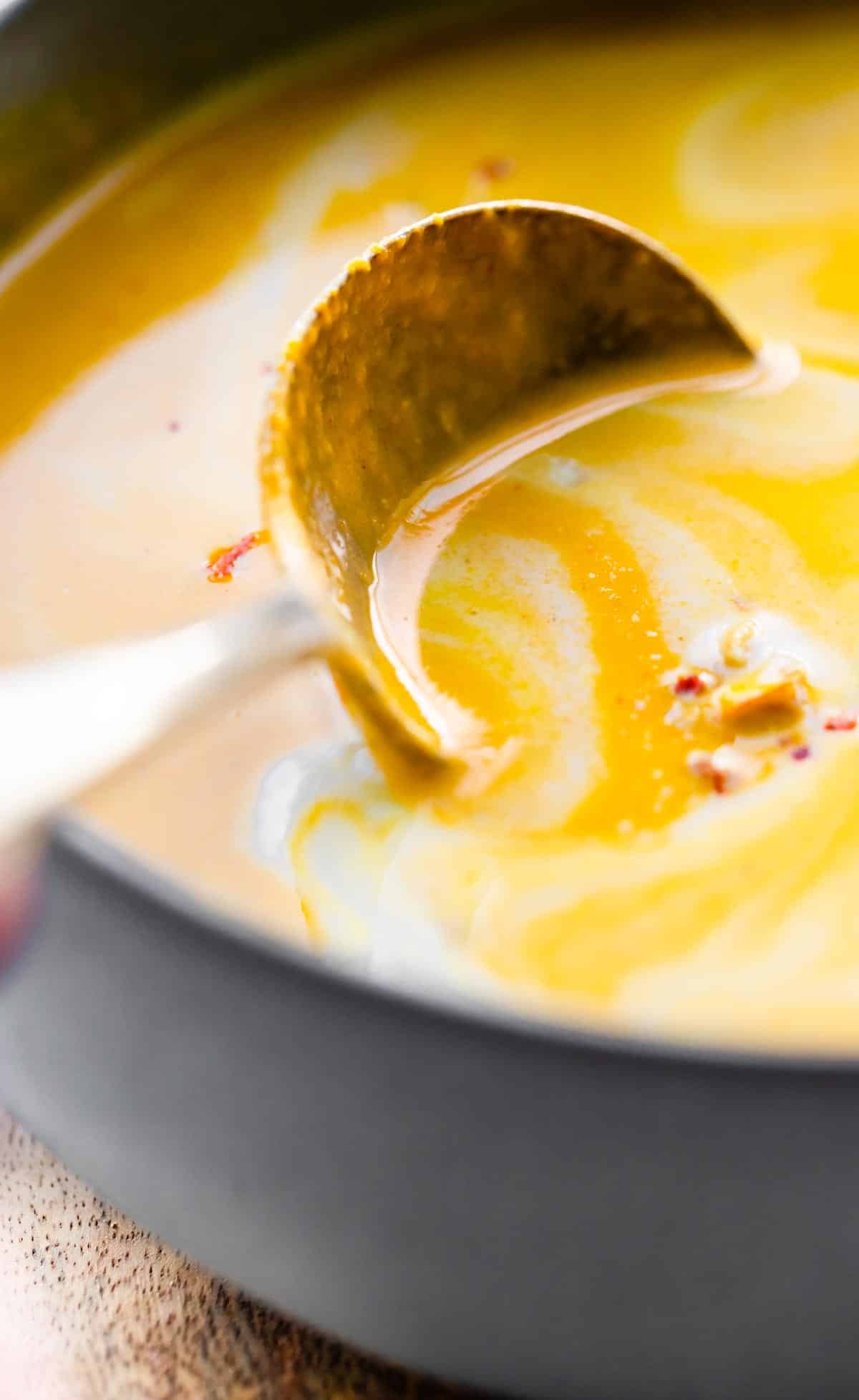 Up close photo of a spoon in a bowl of vegan carrot ginger soup.