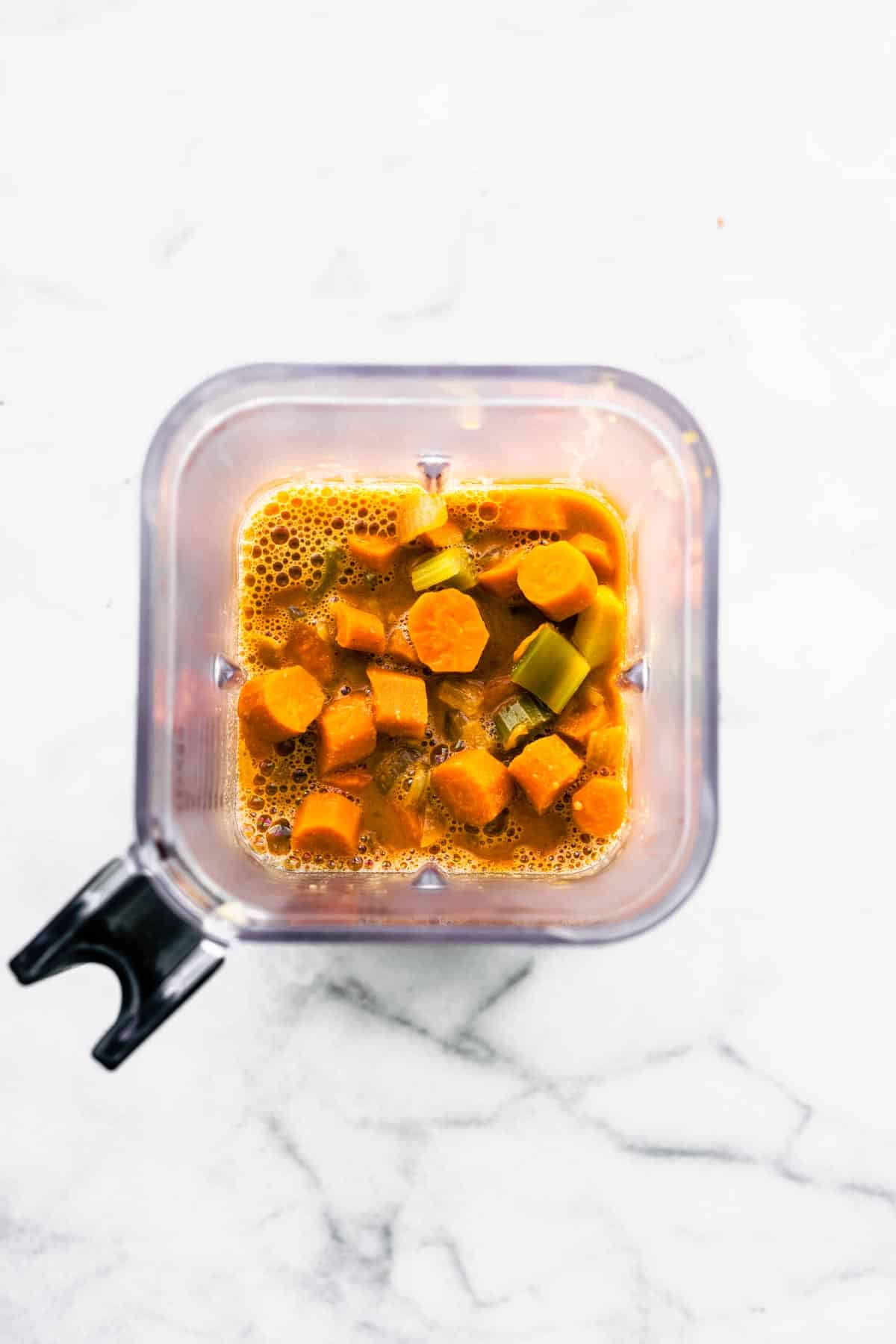 Overhead photo of cooked carrots, celery and broth in a blender.