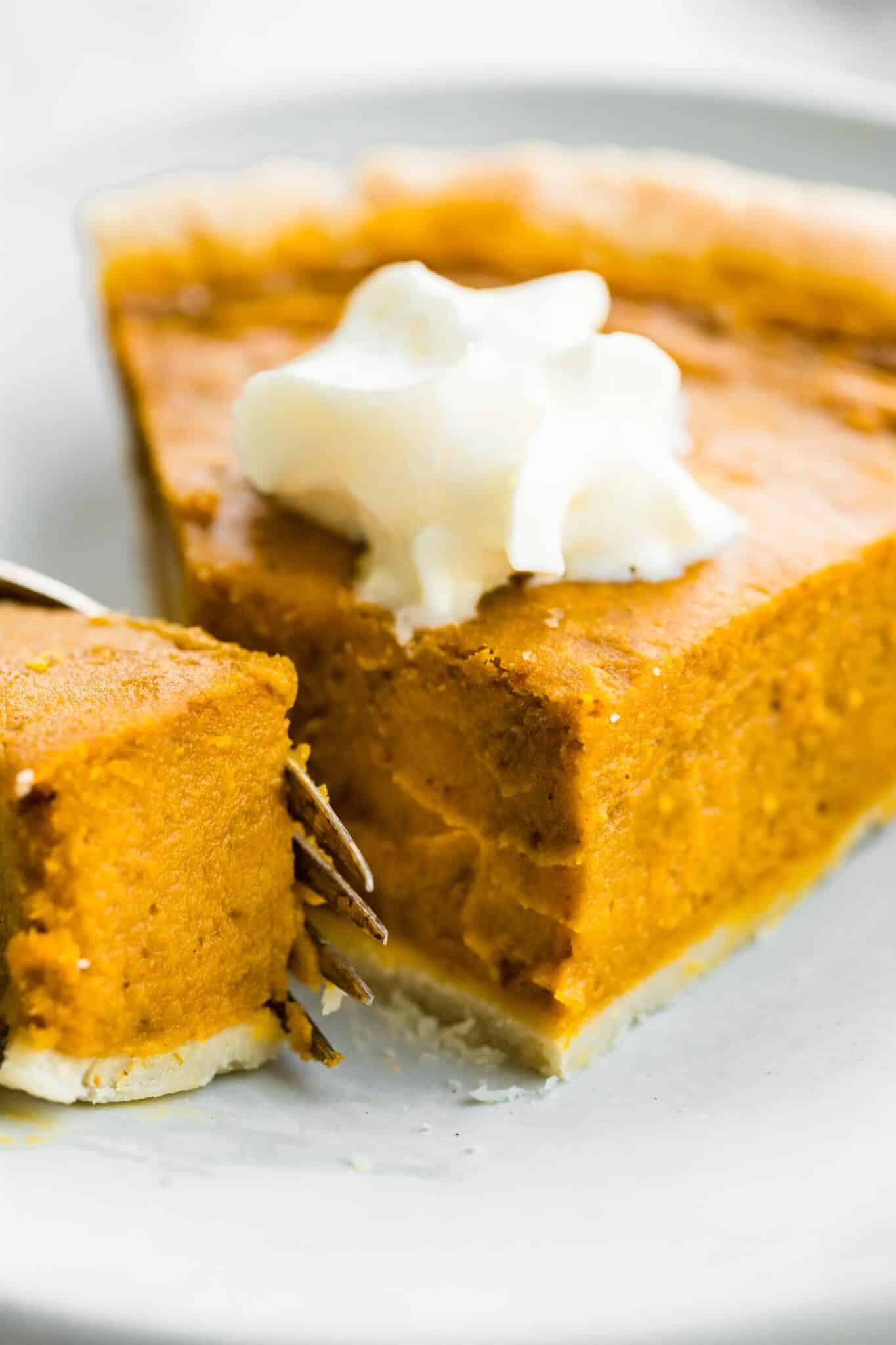 Up close photo of a fork cutting through the tip of a pumpkin pie slice.