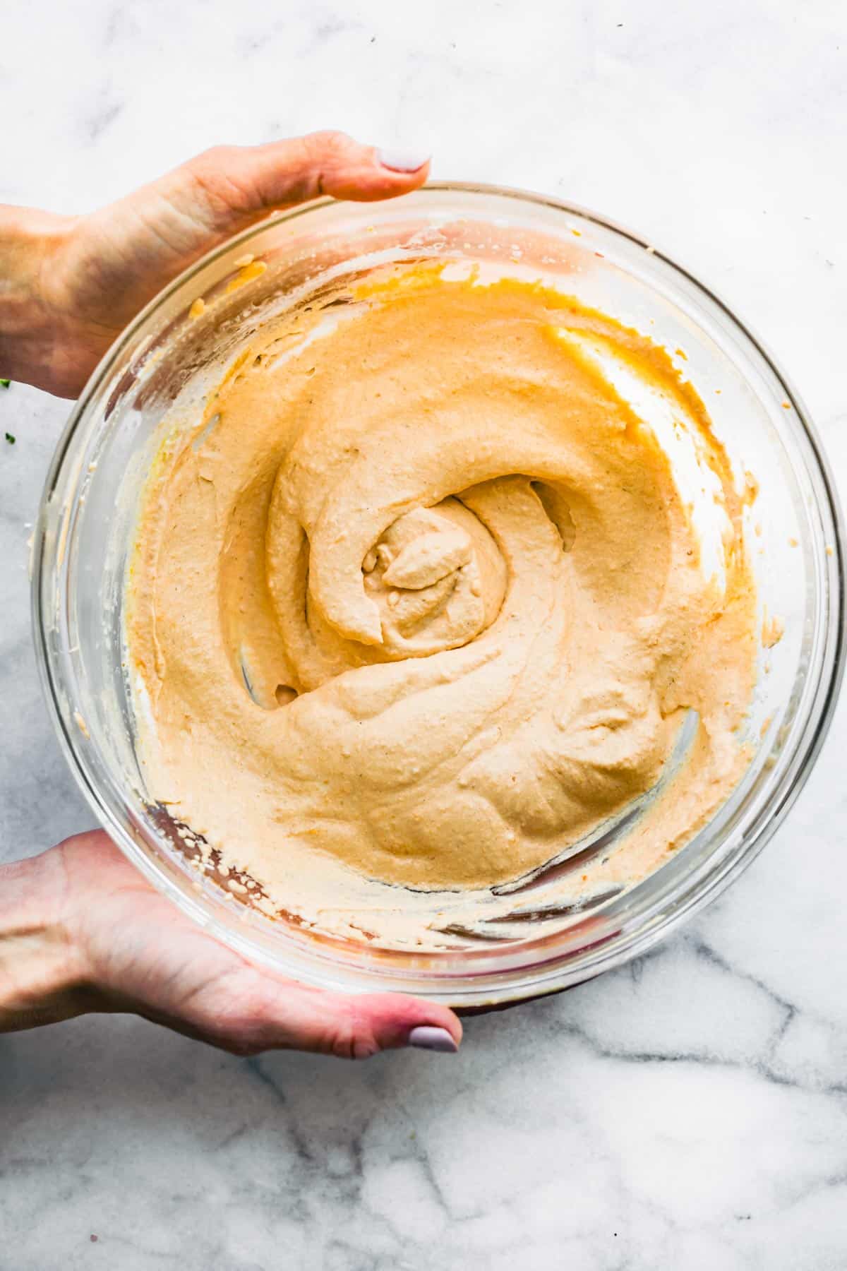 two hands holding a bowl of vegan pumpkin pie dip