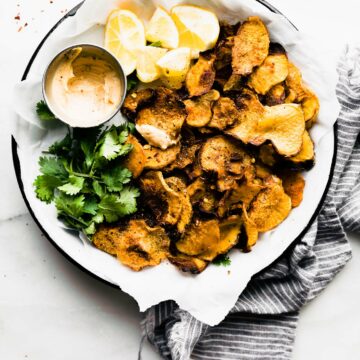 Overhead view pile of baked rutabaga chips on parchment lined round tray