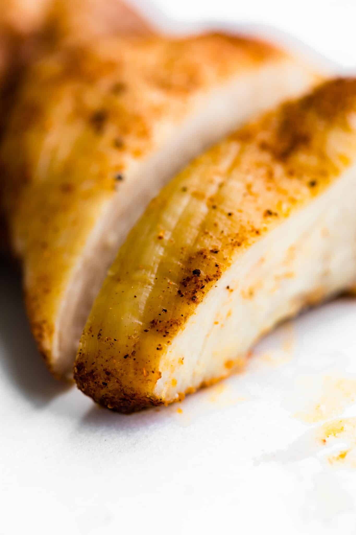 Up close photo of air fried chicken thighs with flecks of spices.
