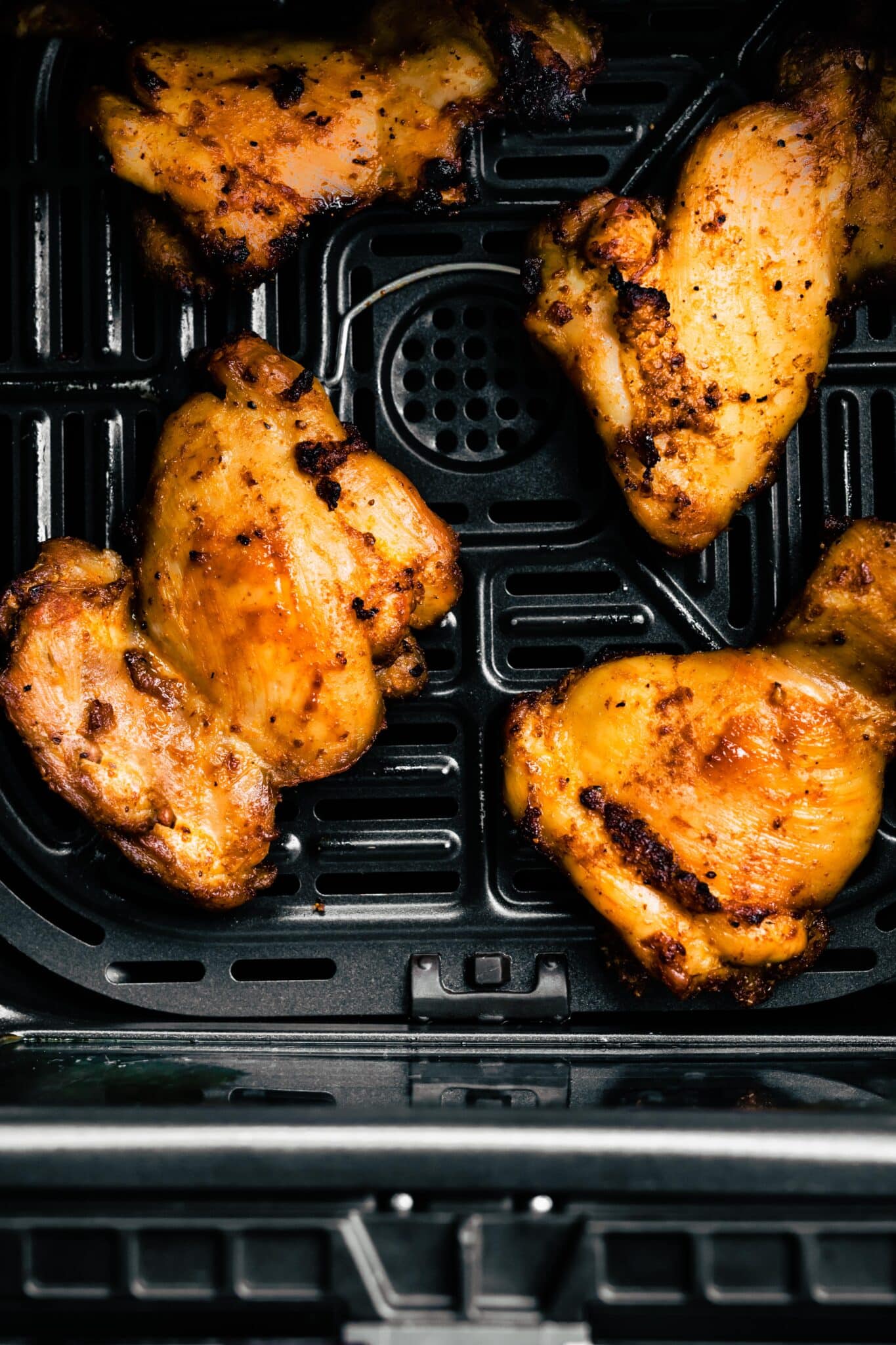Overhead photo of air fryer chicken thighs in an air fryer basket.