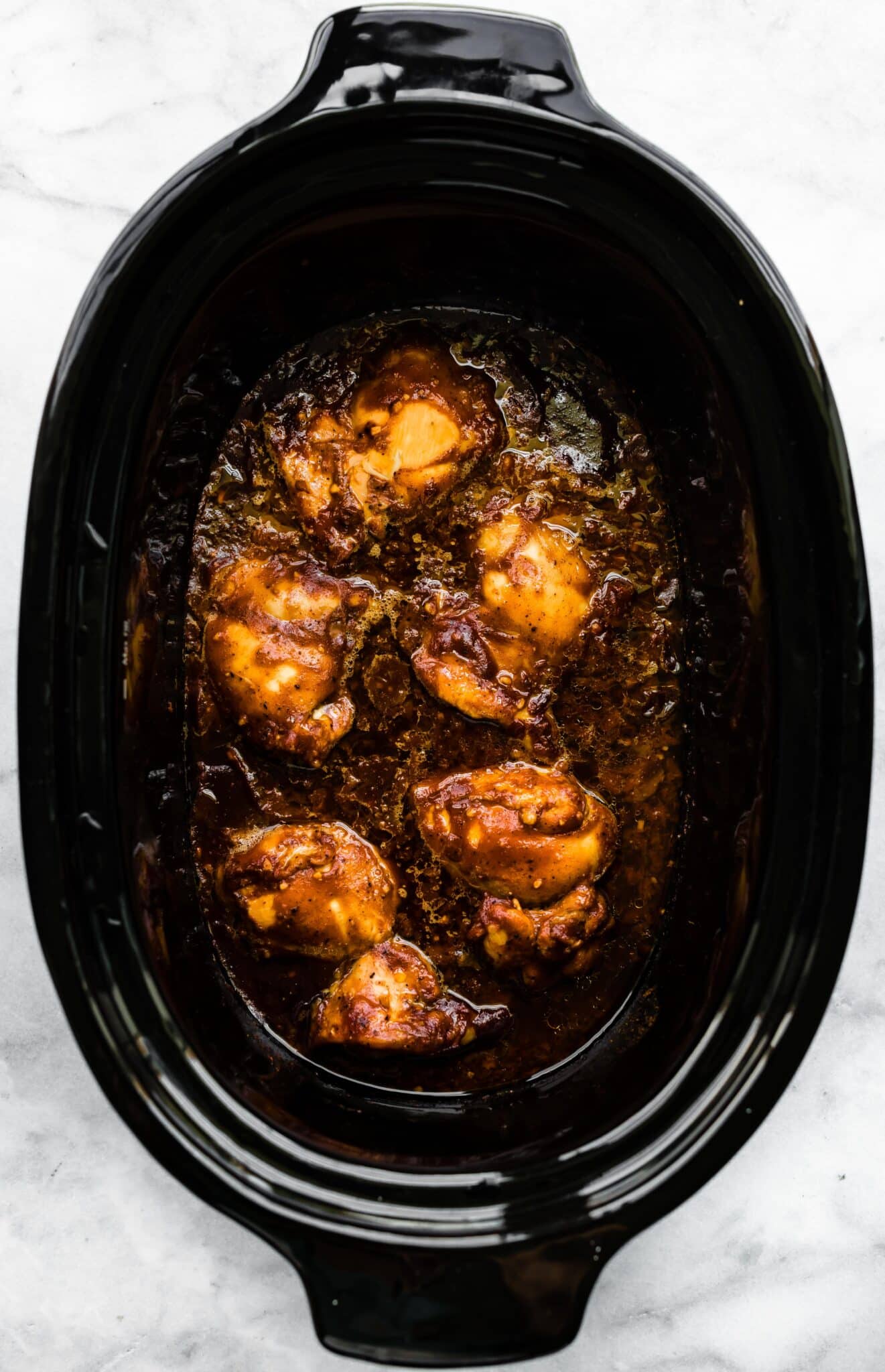 Overhead photo of cooked bbq chicken thighs in a crockpot.