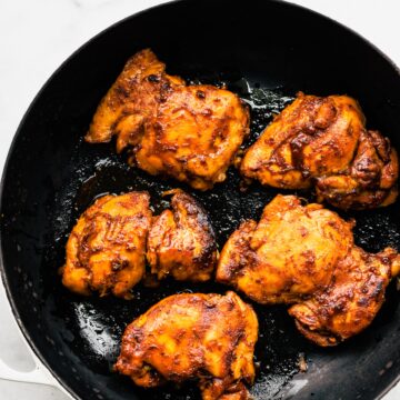Overhead photo of crockpot bbq chicken thighs in a ceramic skillet.