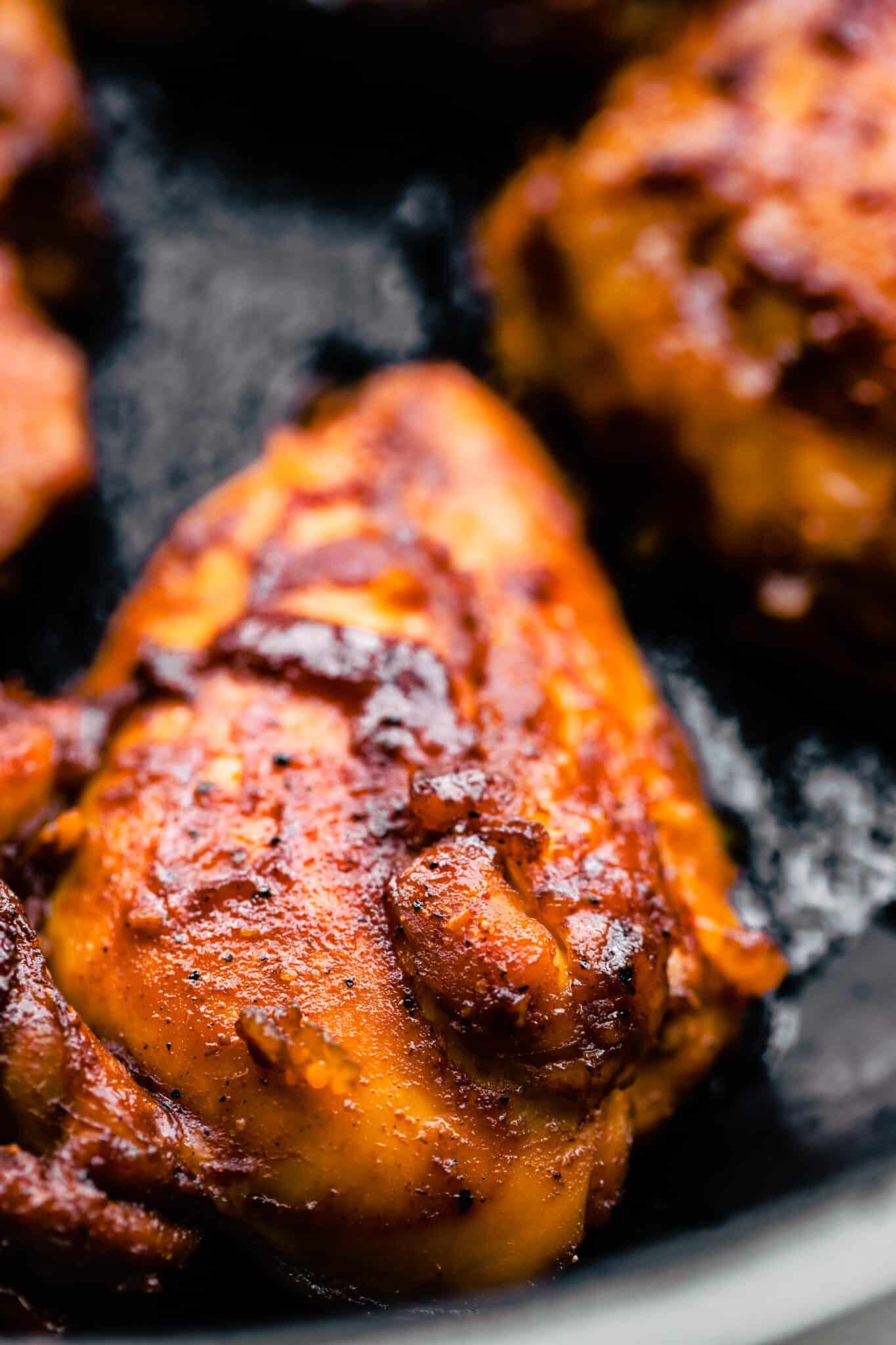 Up close photo of a bbq chicken thigh in a cast iron skillet.