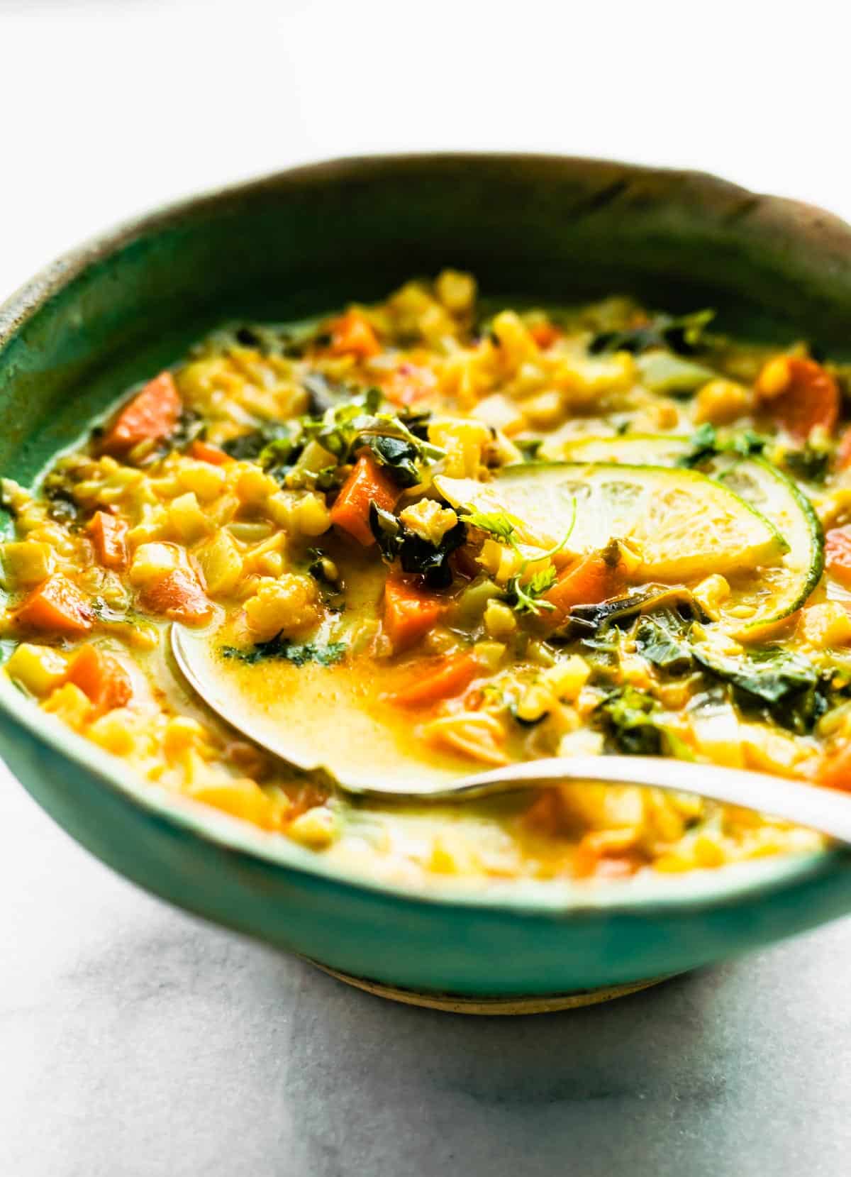 Curried Cauliflower Soup in a bowl with a spoon.