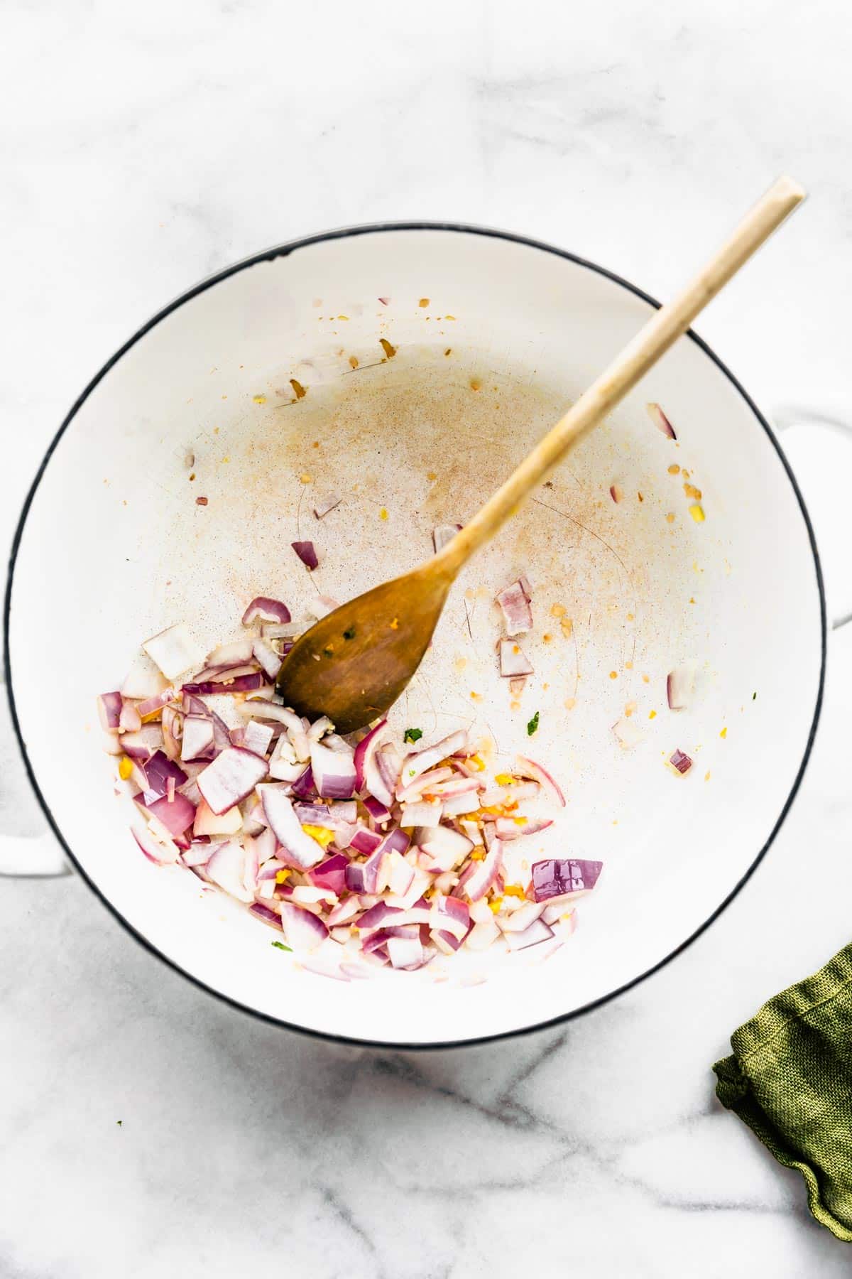 Red onion and garlic being sautéed in a pot.