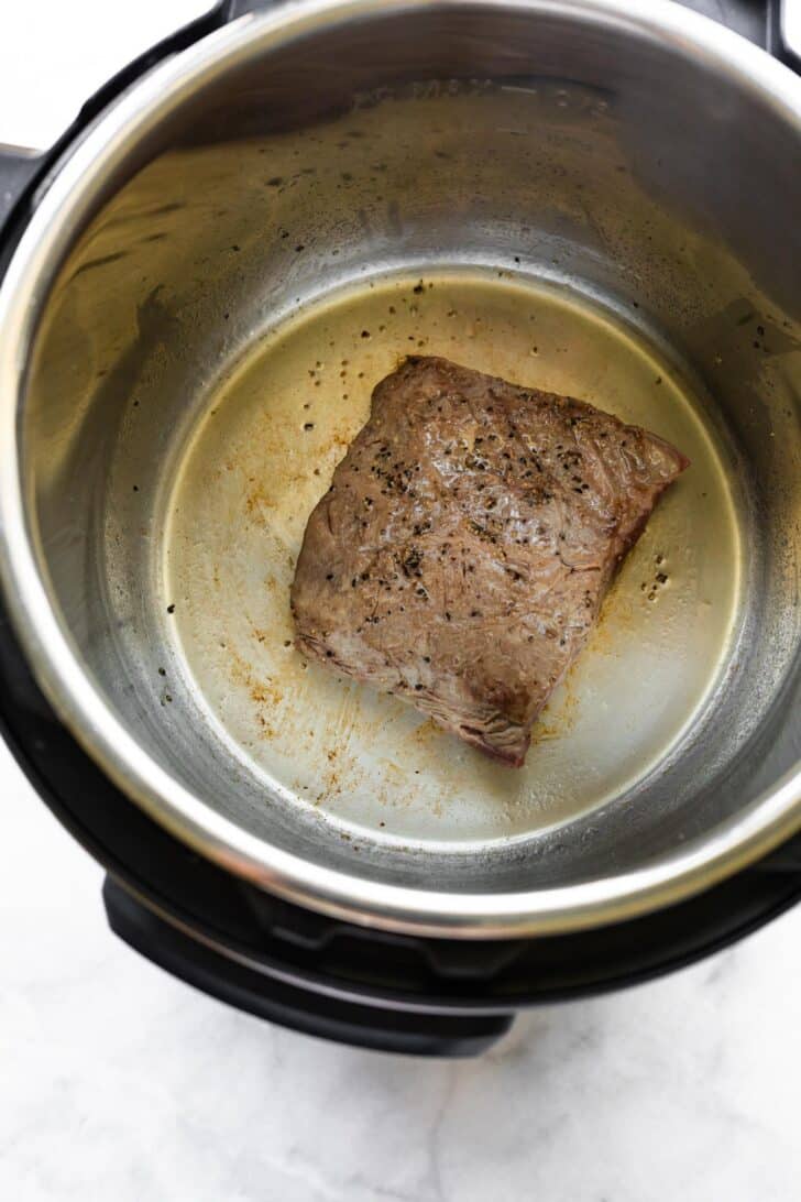 Overhead photo of a steak searing in an Instant Pot.