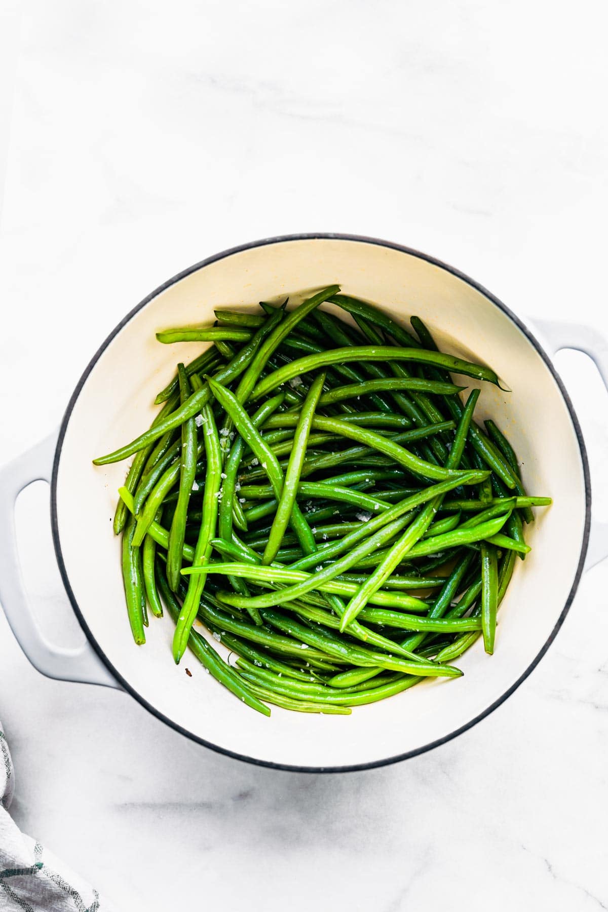 Overhead photo of fresh green beans in a white ceramic pan.