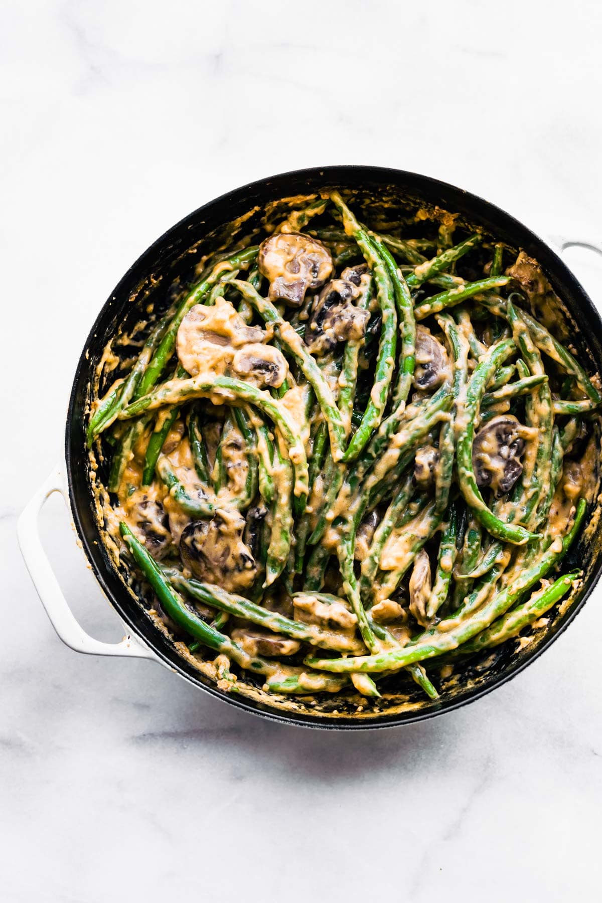 Green beans mixed with a vegan cream of mushroom soup in a black skillet.