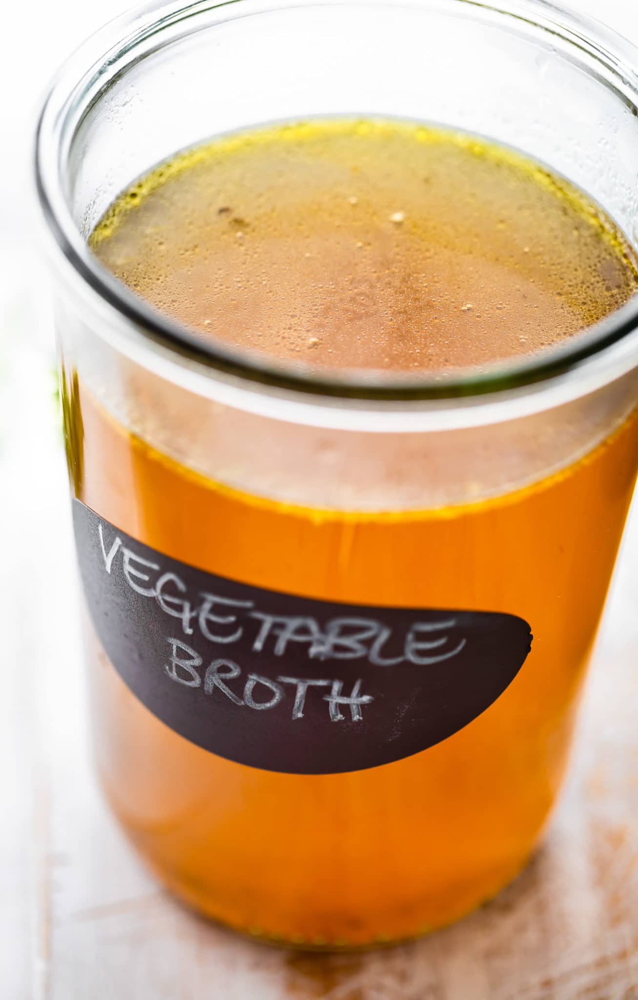 side image of clear vegetable broth in a glass container.