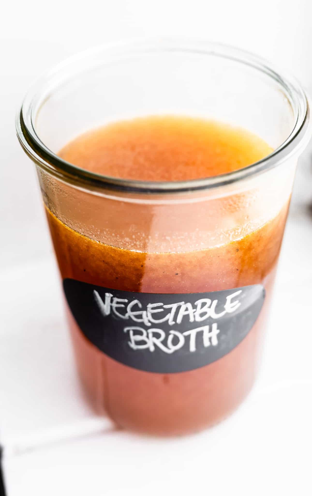 an overhead image of a glass jar filled with homemade vegetable broth.