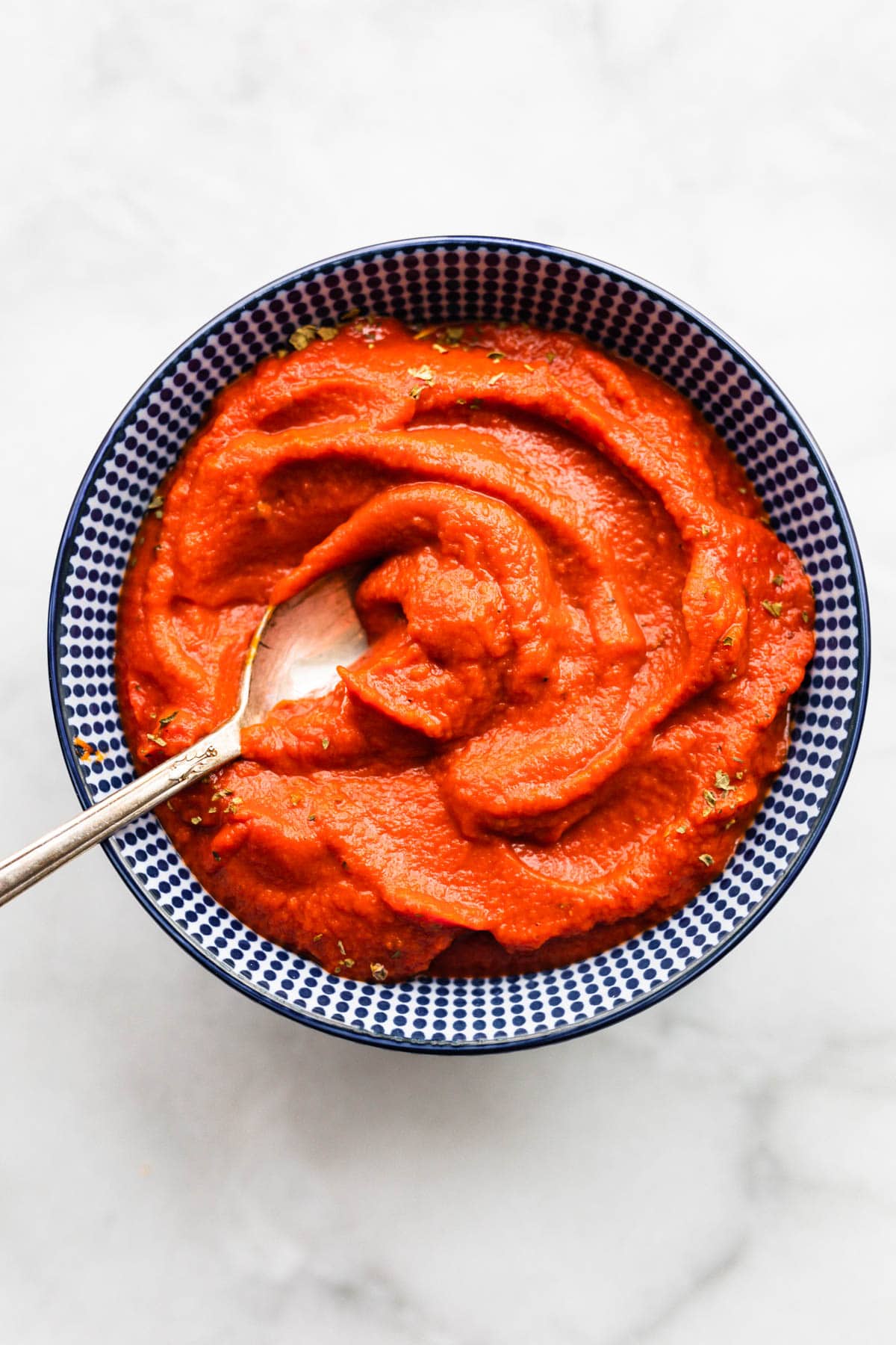 Nomato sauce in a blue and white bowl with a spoon.