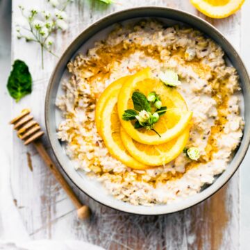 Overnight view orange vanilla protein overnight oatmeal served in stone bowl topped with fresh orange slices