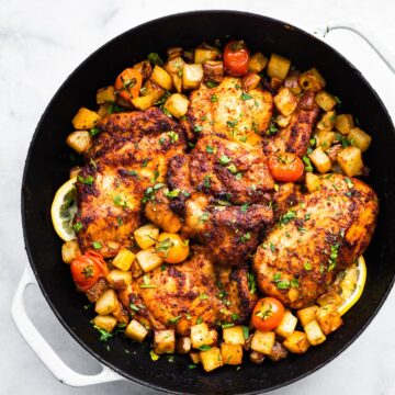Overhead photo of gluten free paprika chicken thighs surrounded by diced veggies in a pan.