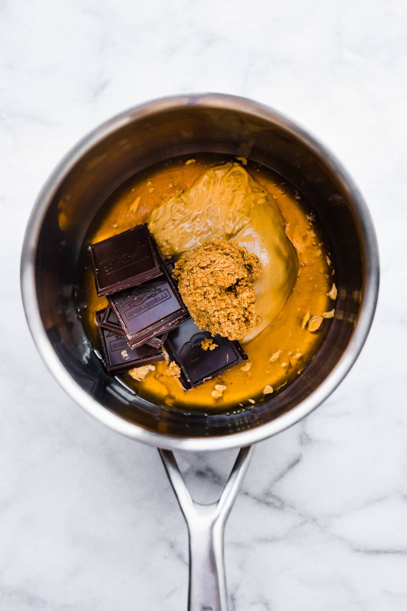 a saucepan with peanut butter, chocolate, and honey ready to be melted and combined to create chocolate peanut butter cornflake cookies