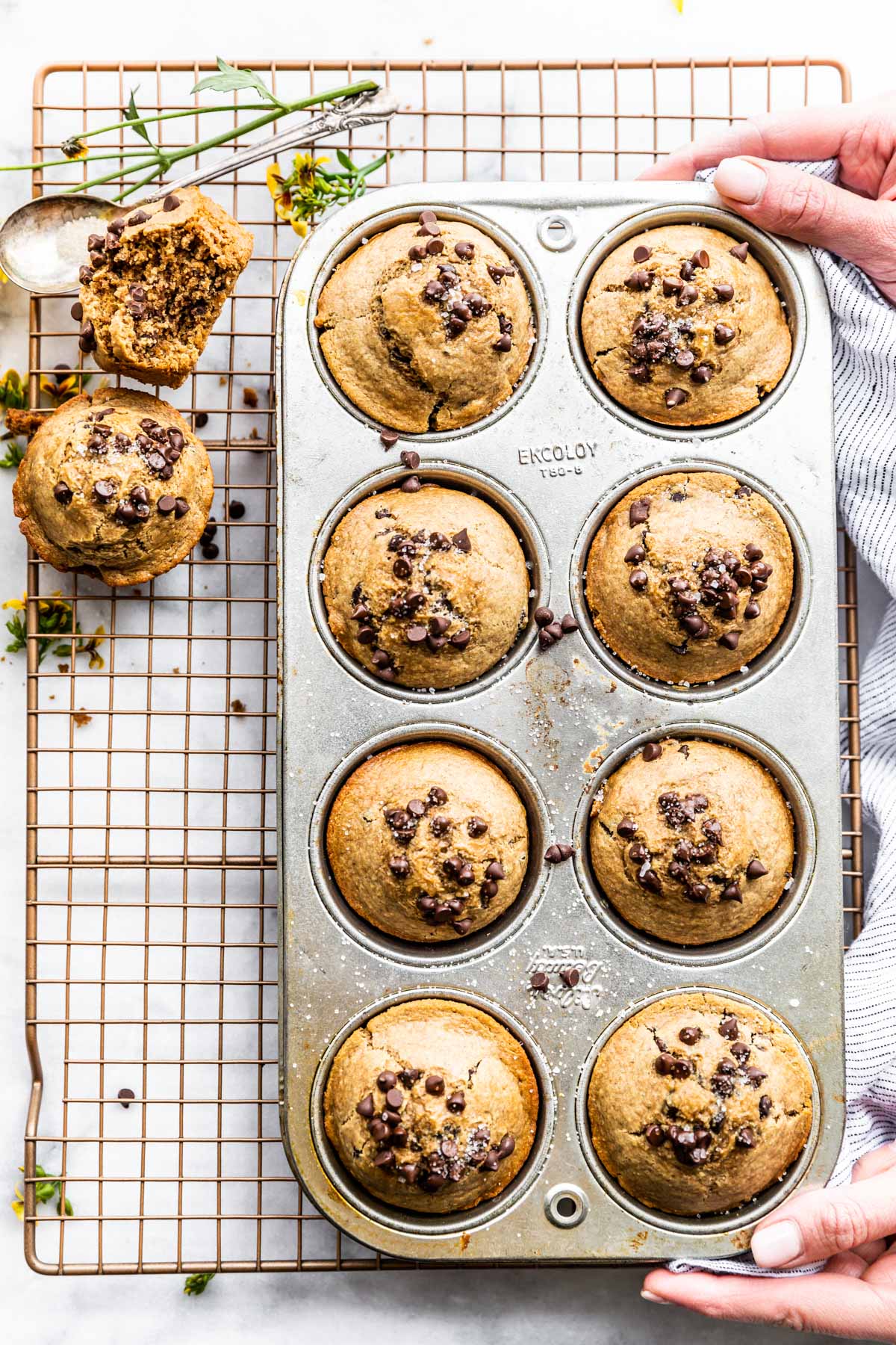 muffins in a pan with hands holding edges