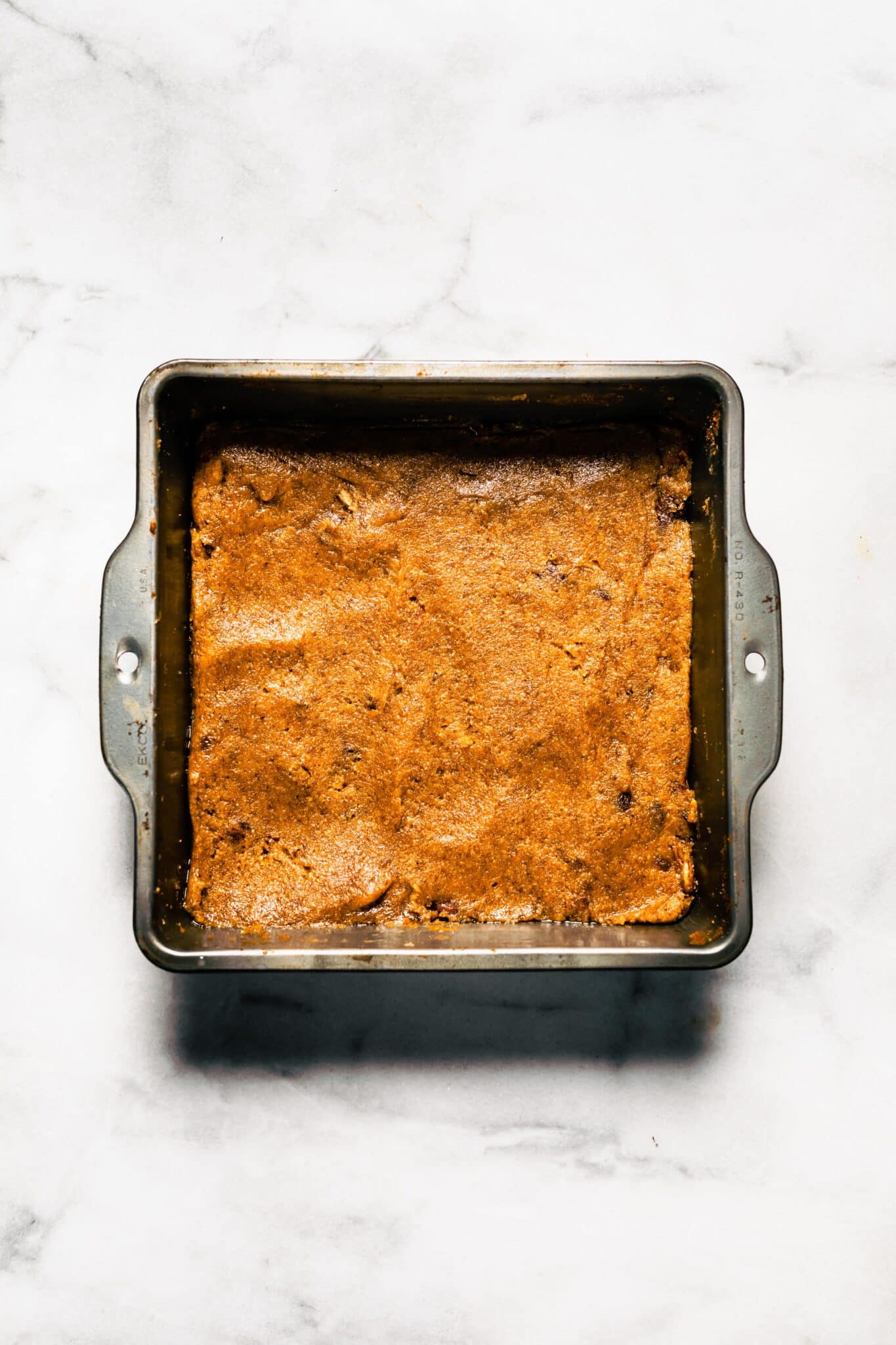 Paleo bar batter in a square metal pan ready to be baked.