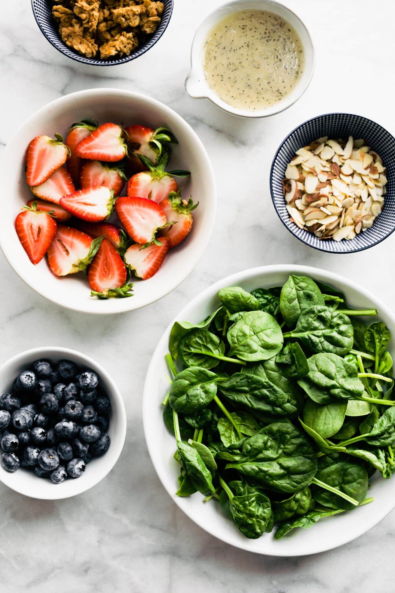 Overhead photo of ingredients for a strawberry spinach salad with granola croutons.