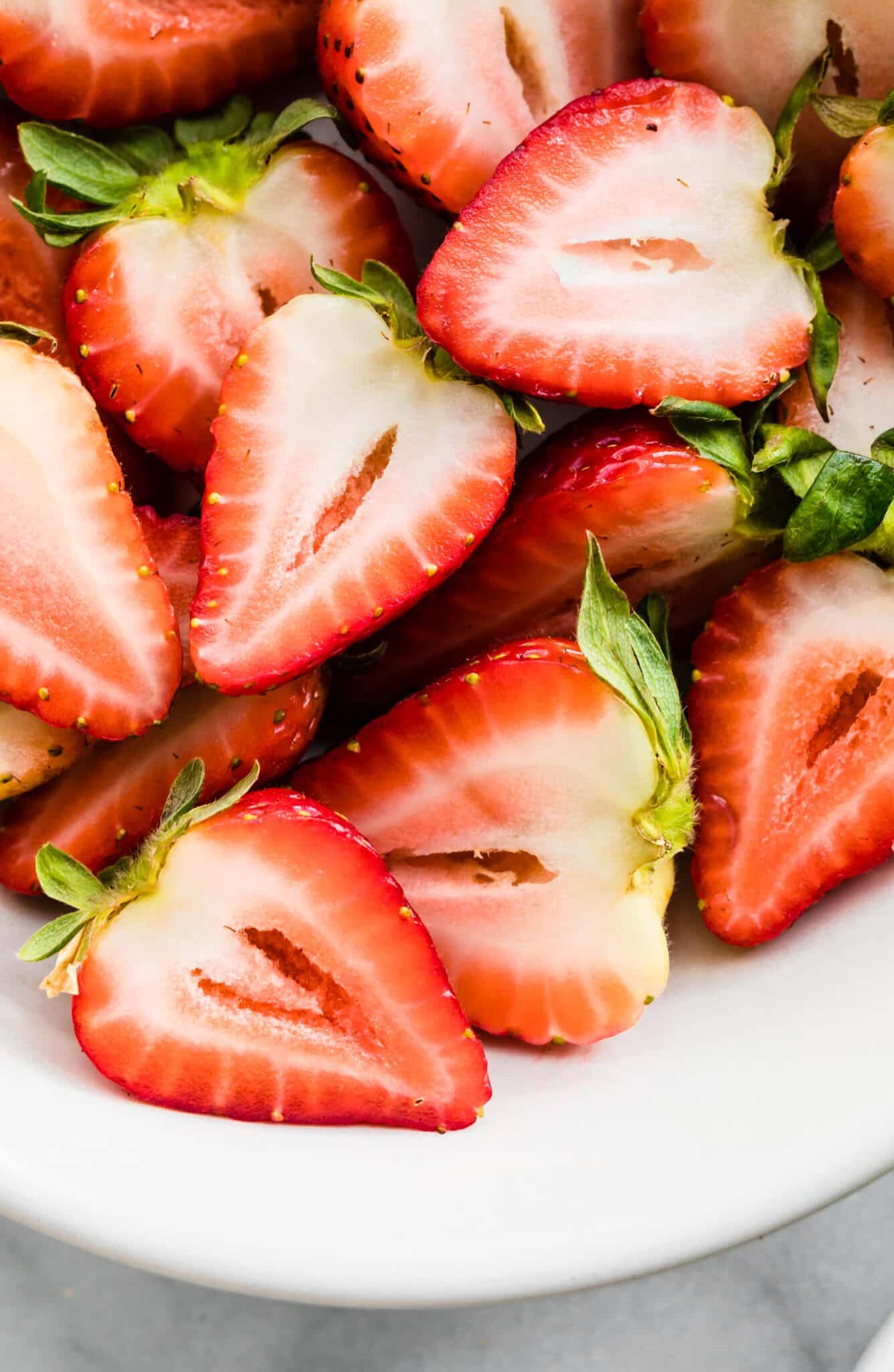 Up close photo of strawberries halves piled together.