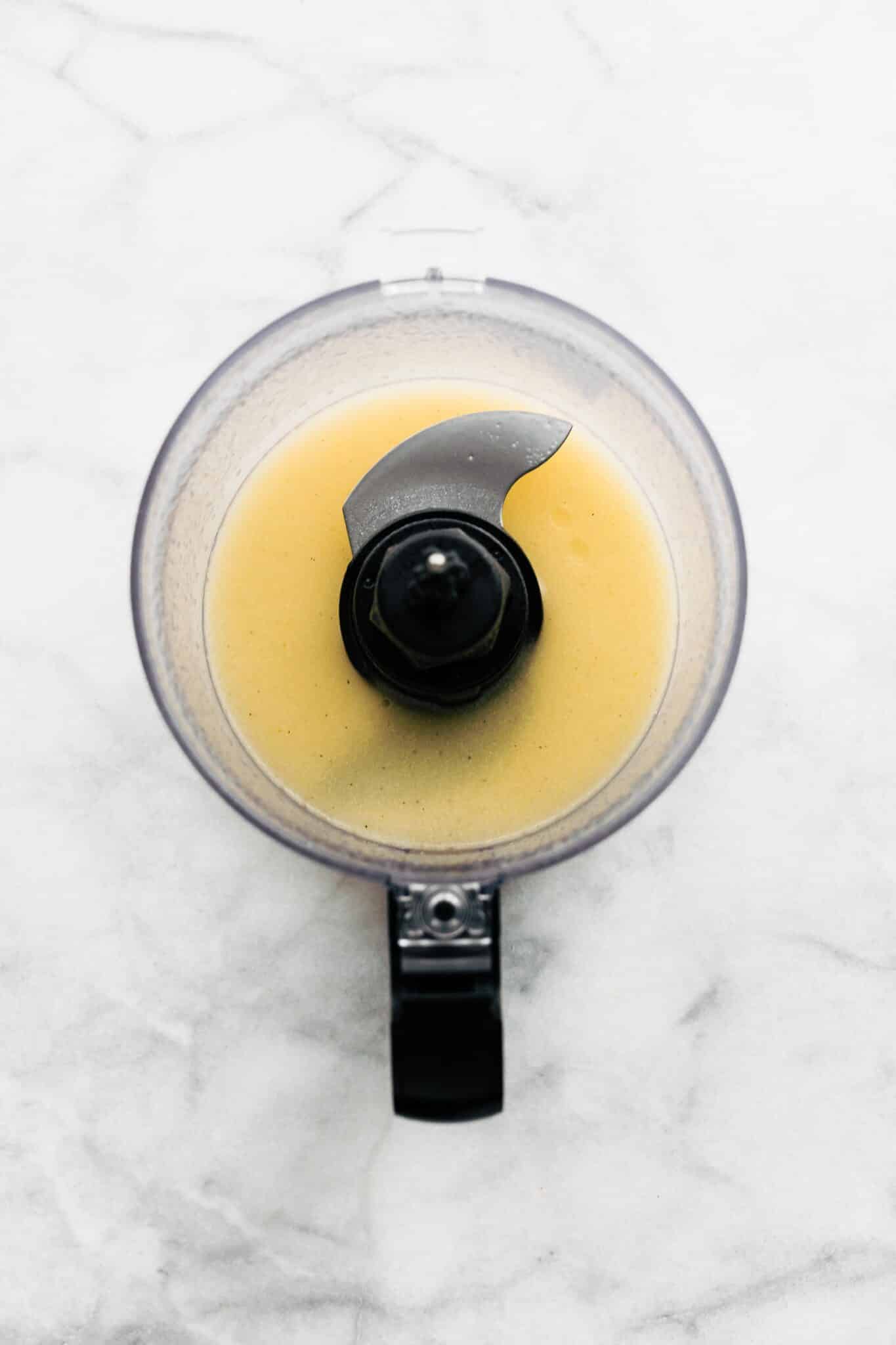 Overhead photo of a small food processor with a homemade yellow salad dressing.