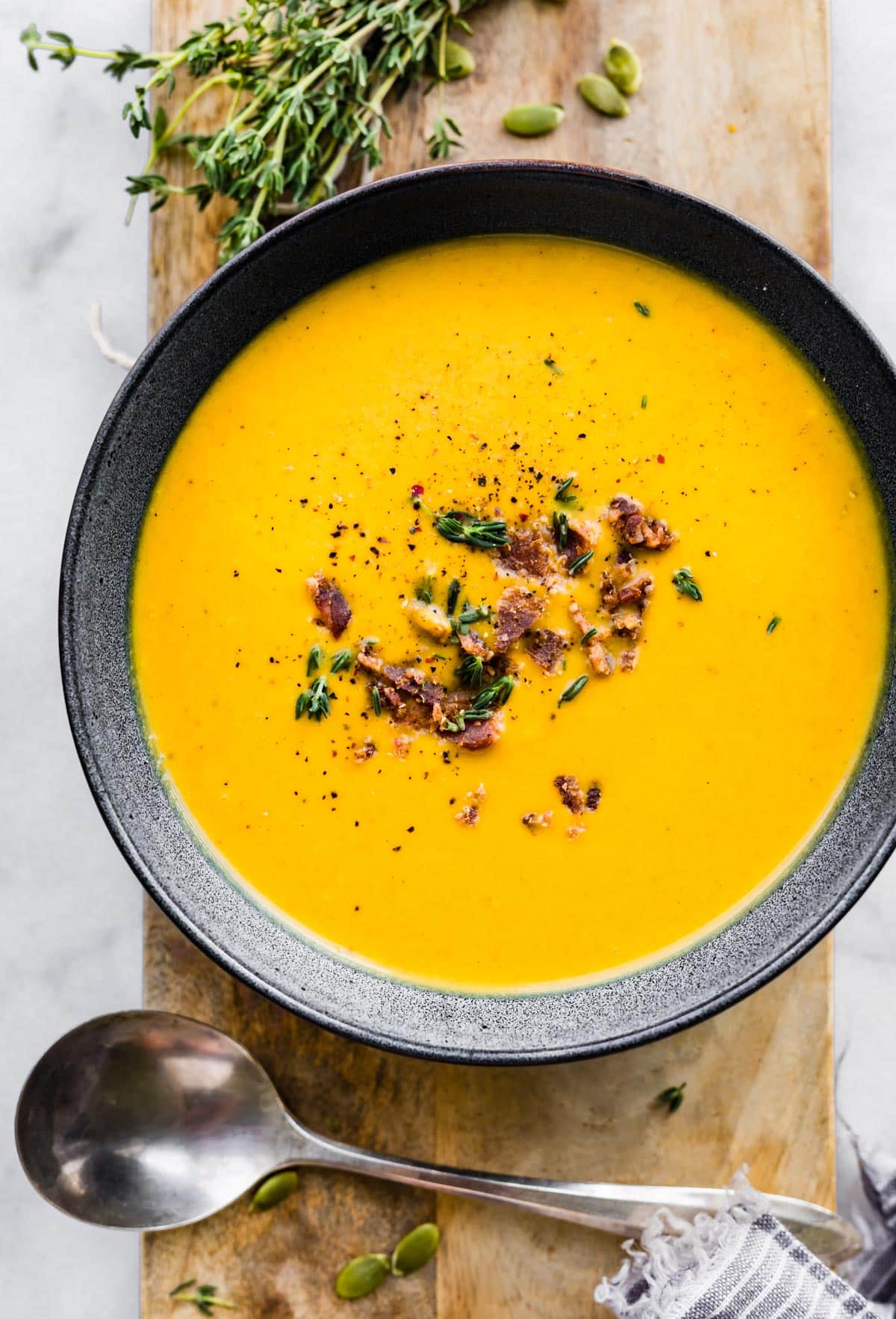 Overhead photo of a bowl of butternut squash soup and a spoon on the side.