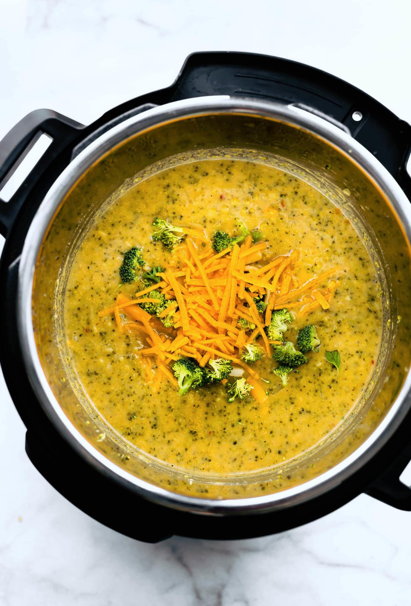 Vegan broccoli cheese soup in an instant pot topped with shredded dairy-free cheese.