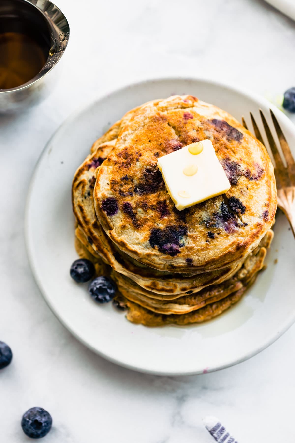 overhead: large stack of blueberry vegan protein pancakes with pat of butter on top