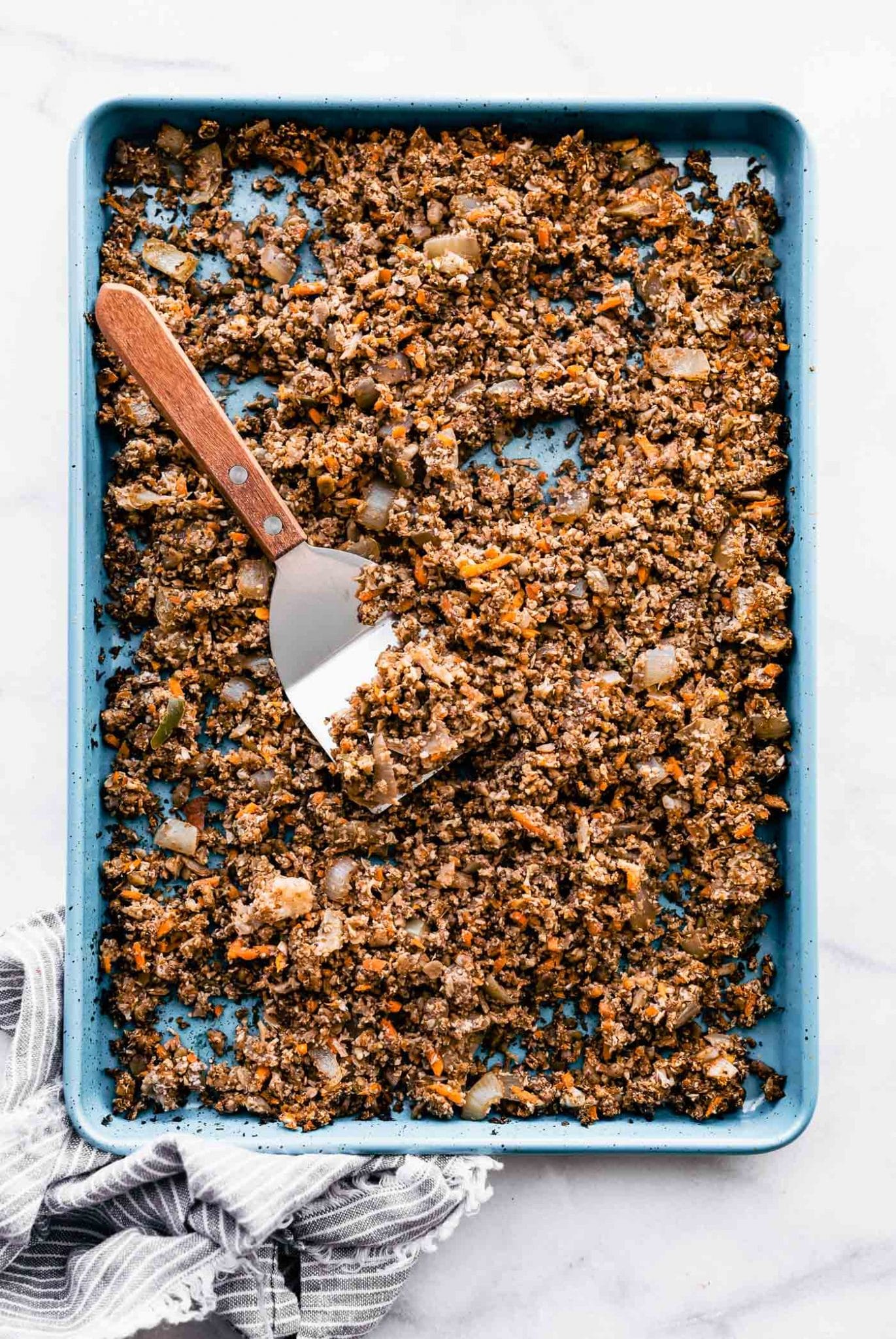 Overhead image of vegan taco meat on a sheet pan with a spatula for serving.