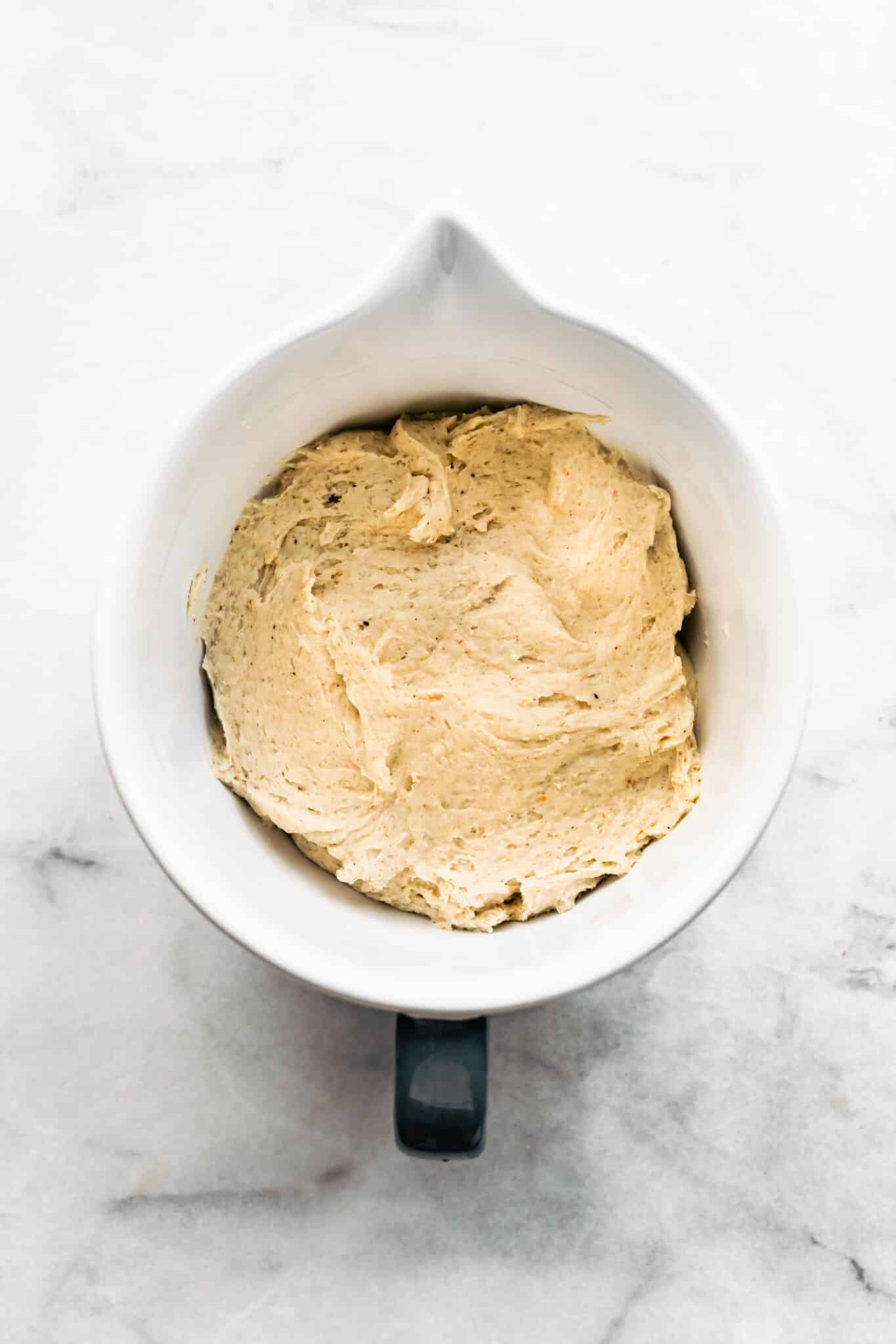 gluten free cinnamon roll dough in white mixing bowl, before rising
