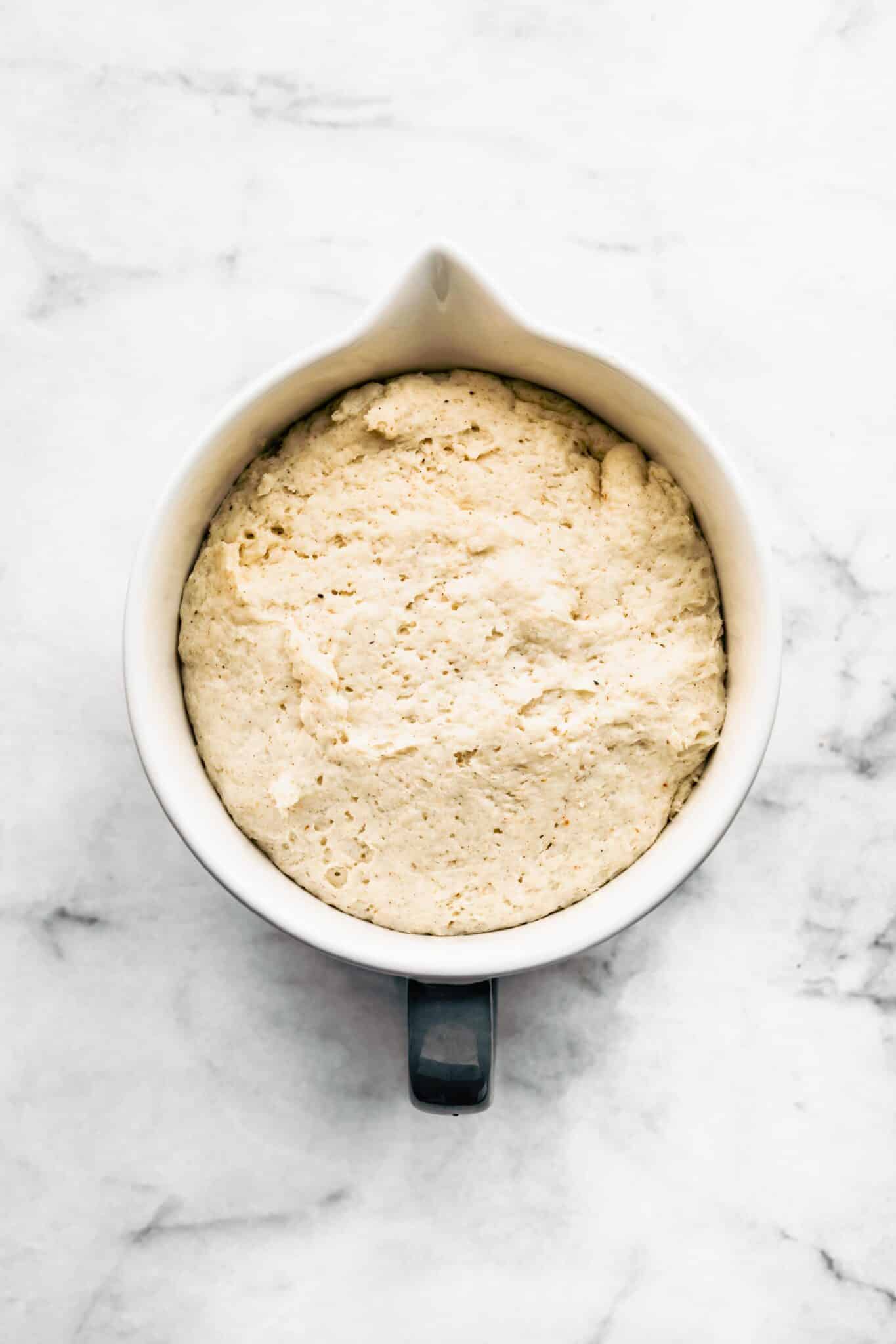 gluten free cinnamon roll dough rising in white mixing bowl