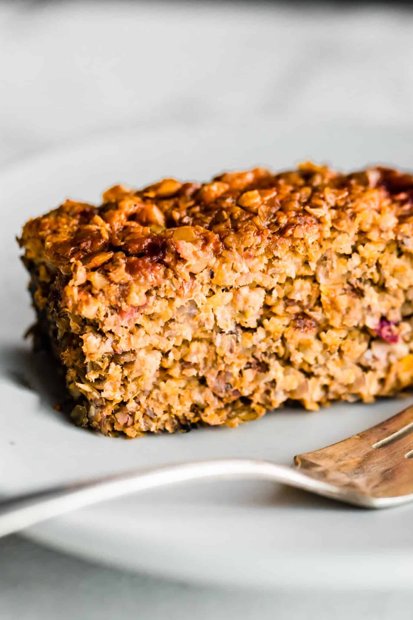Up close side shot of a piece of lentil loaf on a plate with a fork.