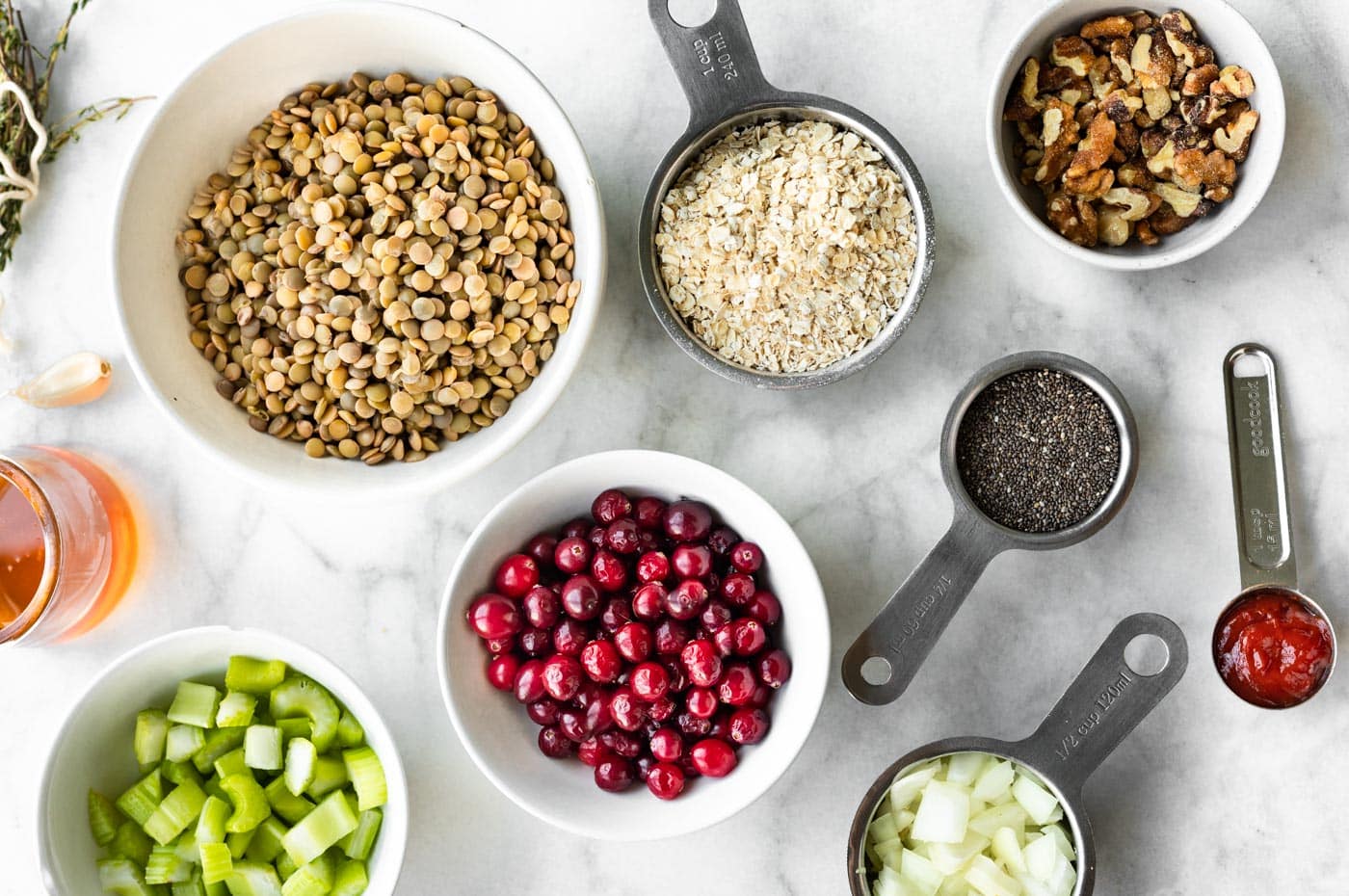 Overhead photo of ingredients in bowls for a holiday lentil loaf on a white countertop.
