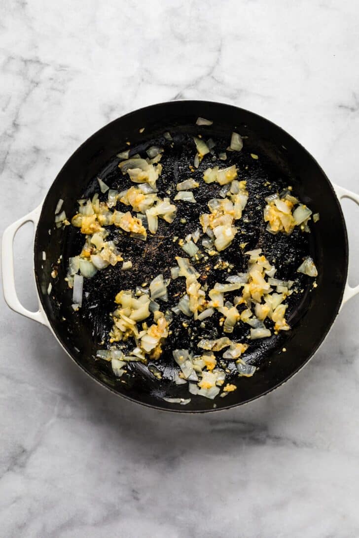 diced onion and garlic sauteed in a black skillet