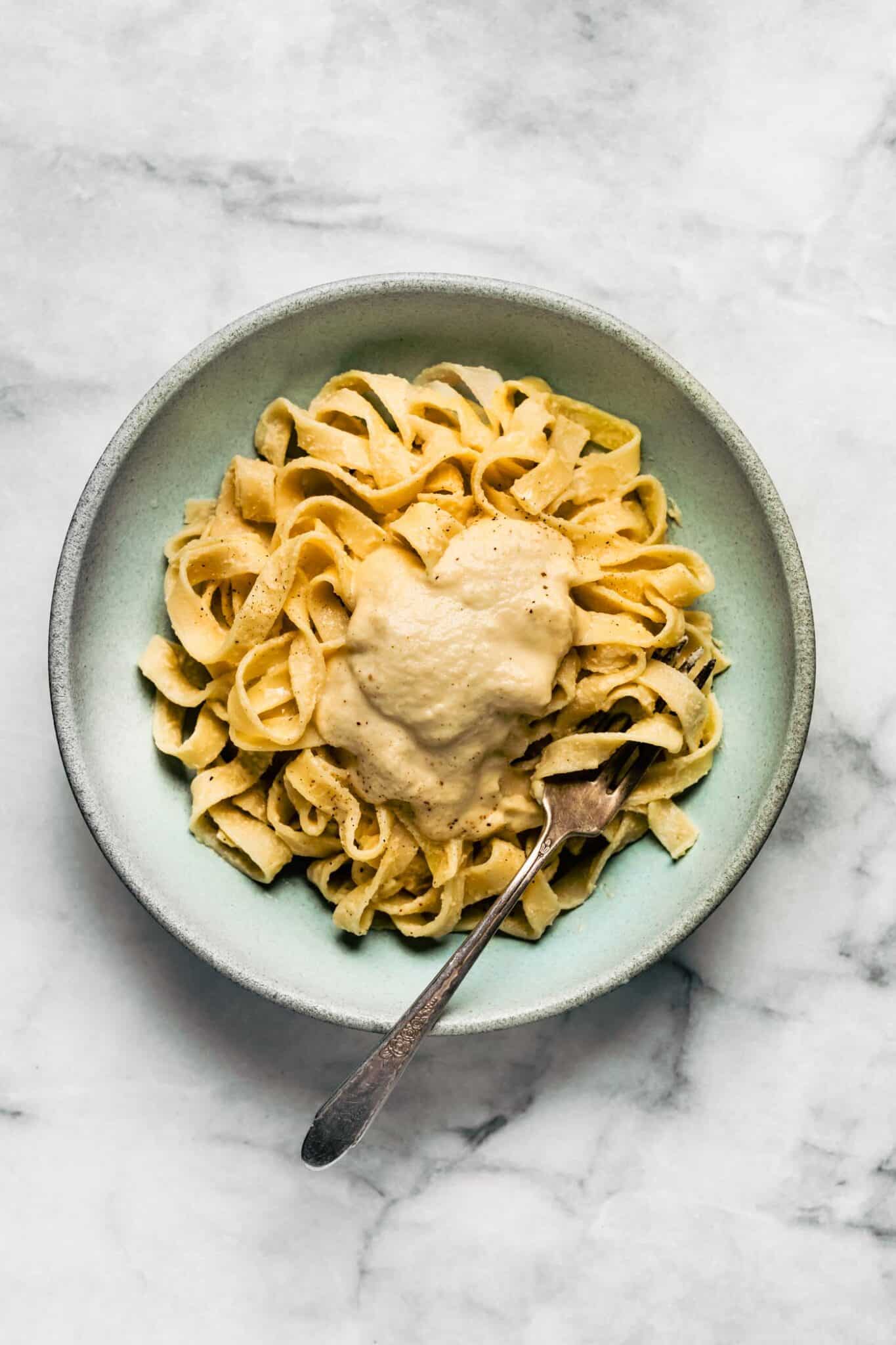 light blue bowl of gluten free pasta with dairy free alfredo pasta sauce