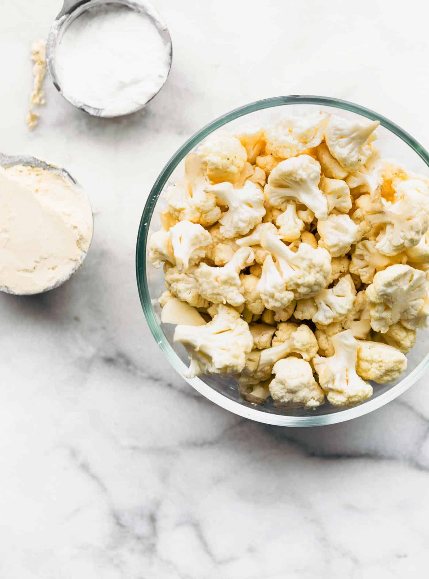 Cauliflower florets, oat flour and potato starch in bowls.