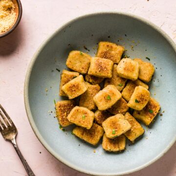 Cauliflower gnocchi in a blue bowl sprinkled with parsley.