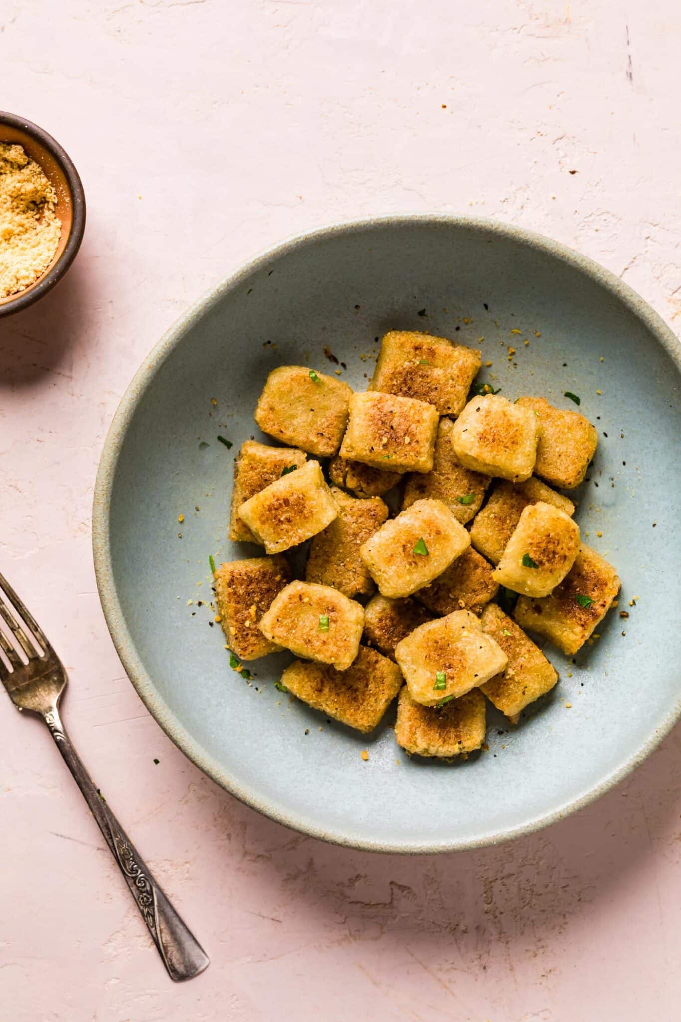 Cauliflower gnocchi recipe served in a blue bowl sprinkled with parsley.