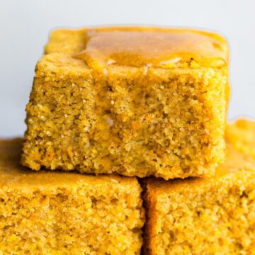 Stacked squares of gluten-free cornbread with a drizzle of honey on top
