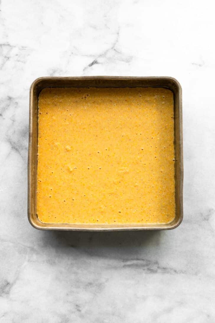 square baking pan filled with smooth gluten-free cornbread batter, ready to be baked.
