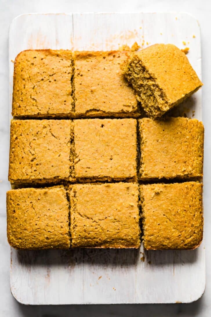 Close-up overhead shot of gluten-free cornbread squares arranged on a rustic white surface
