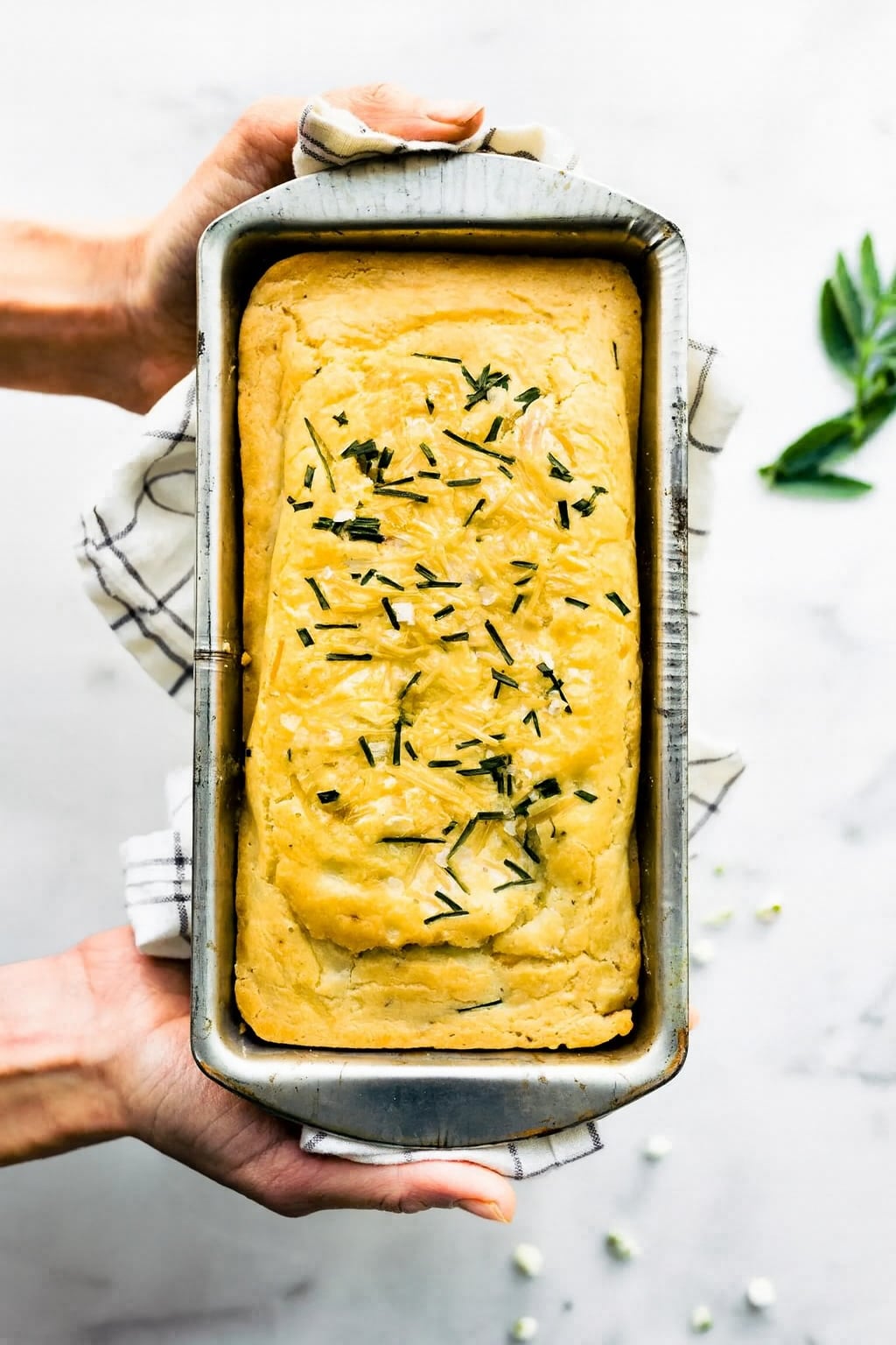 A woman holding a loaf pan of gluten free potato bread.